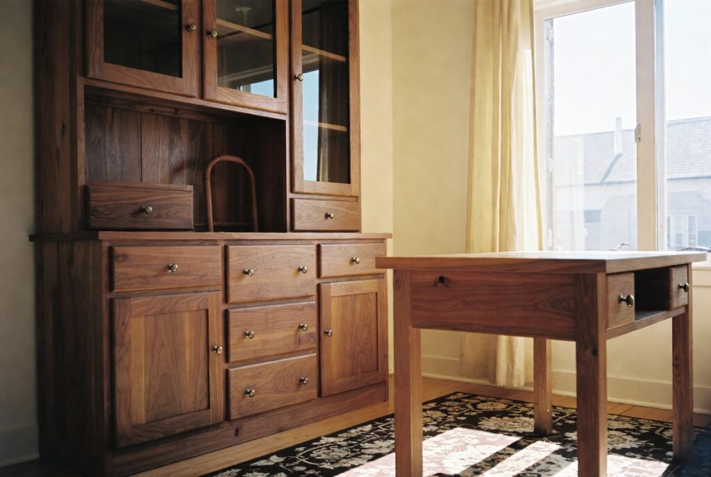 Living room with rich natural walnut wood furniture against warm ivory walls, soft daylight, candid shot