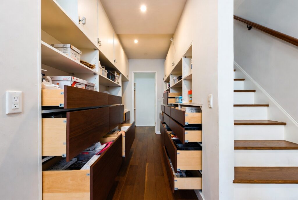 Beautifully fitted under-stair storage with built-in drawers and shelves in home hallway, natural light, organized design