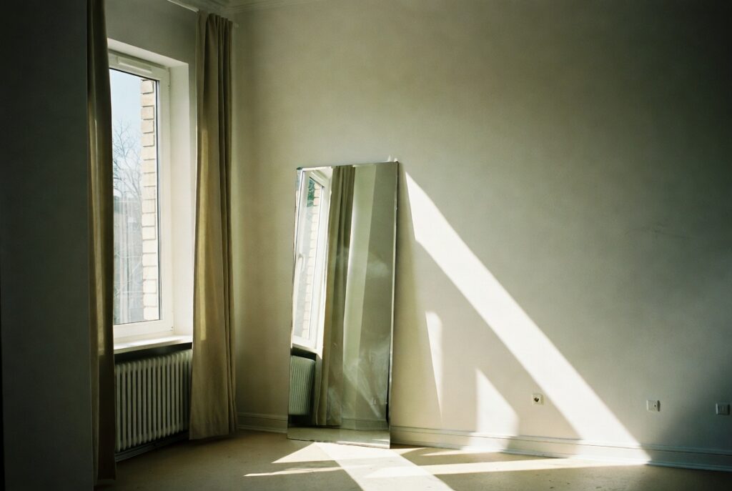 Sunlit room with mirror bouncing bright natural daylight across light walls and floors, airy and fresh
