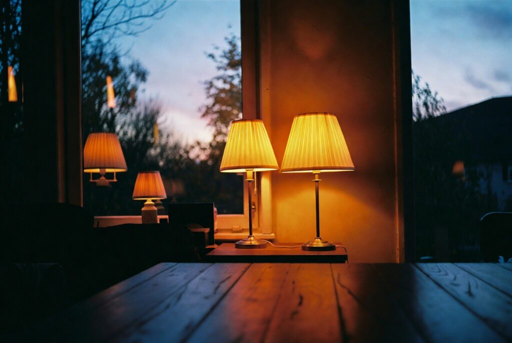Cozy room glowing with warm-toned lamps at different heights on autumn evening, golden ambient light