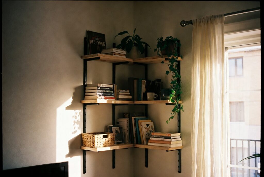 Floating corner shelves in living room styled with books, plants and small basket, warm afternoon light, cozy decor