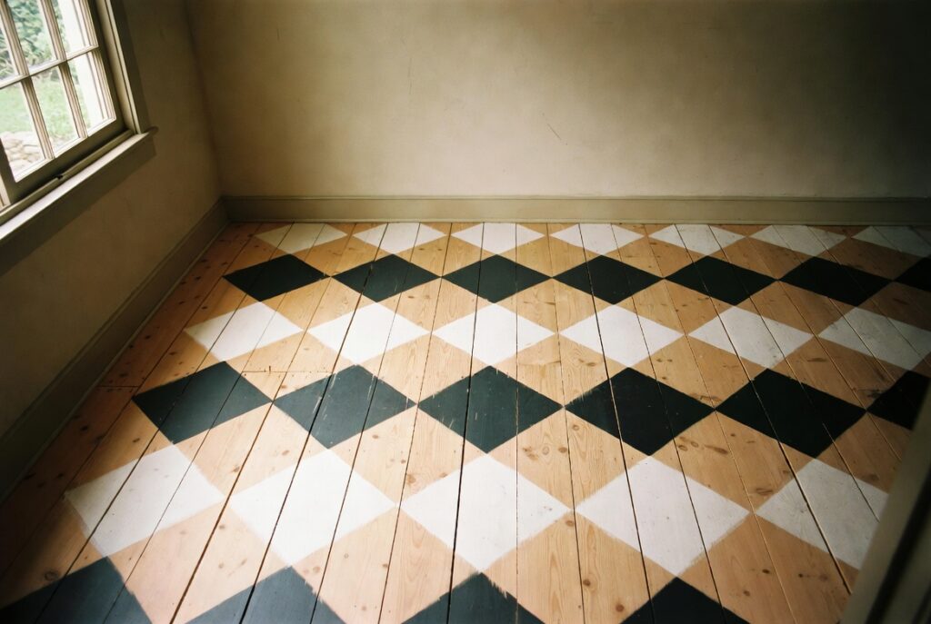 Wooden floor painted with bold black and white diamond pattern in charming cottage room, natural light