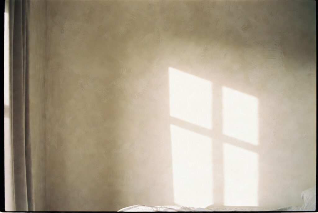 Bedroom with warm cream limewash wall finish showing layered depth and organic texture, soft morning light