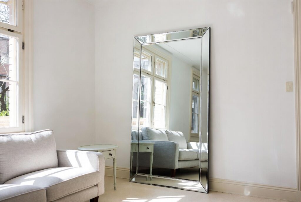 "Hang a large mirror to make small room look bigger - Statement wall mirror doubling the space in bright modern living room with natural light reflection"