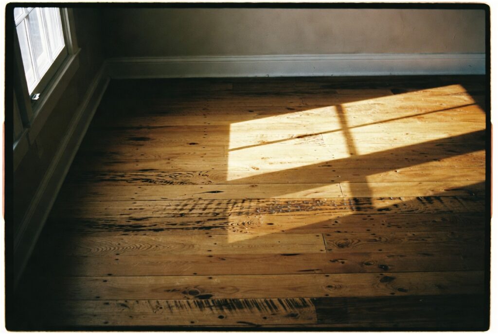 Living room with wide plank reclaimed oak floors showing nail holes saw marks and rich aged patina, warm afternoon light