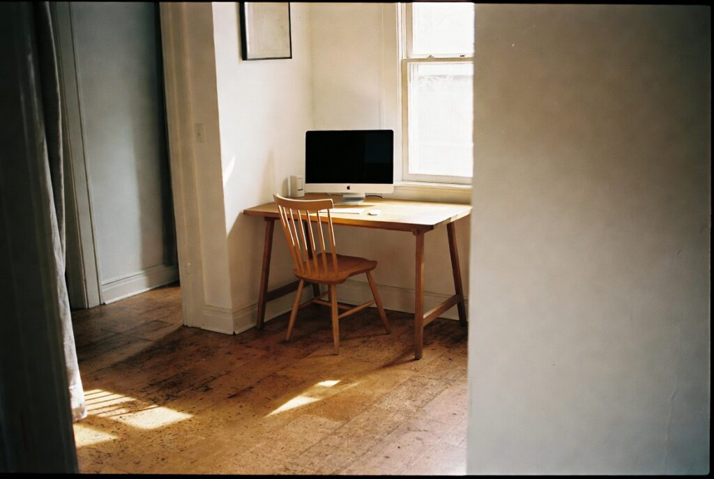 Home office with warm cork flooring showing natural texture, minimal desk setup, natural window light