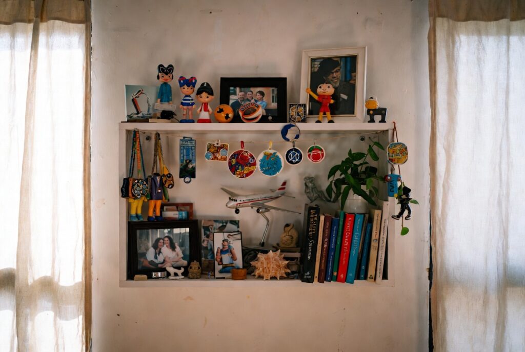 Personal shelf styled with travel souvenirs, family photos and beloved books in warm home, natural light