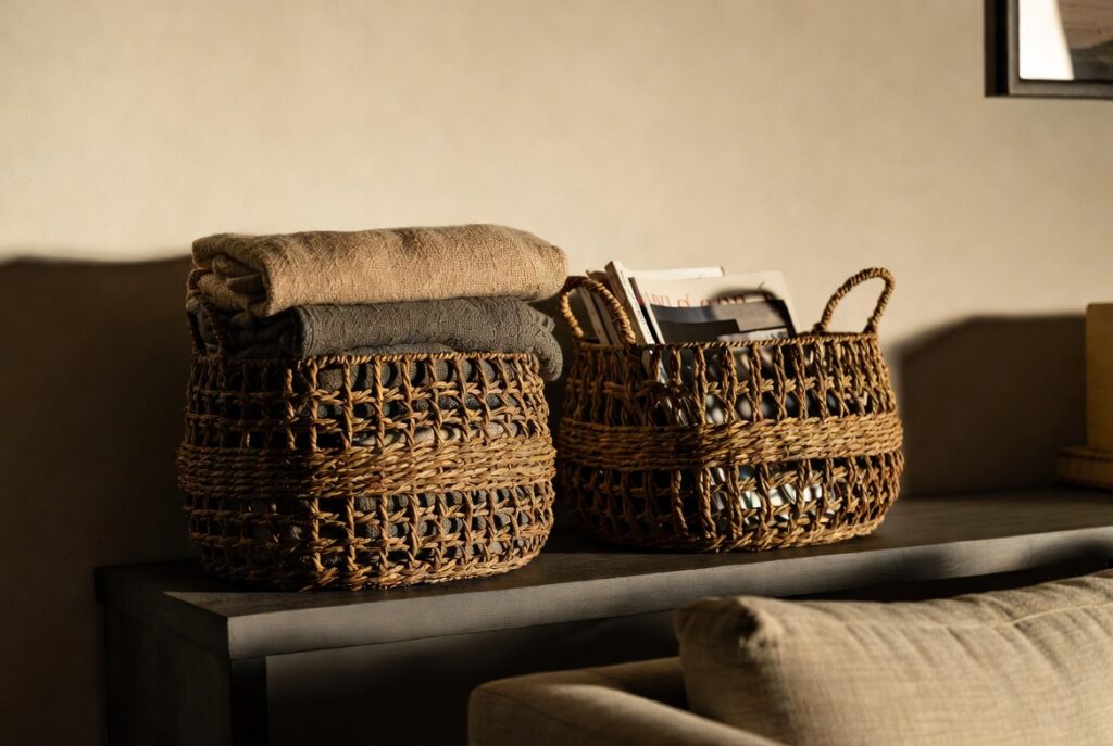 Living room shelf with large woven seagrass baskets holding blankets and magazines, warm afternoon light, organized home decor