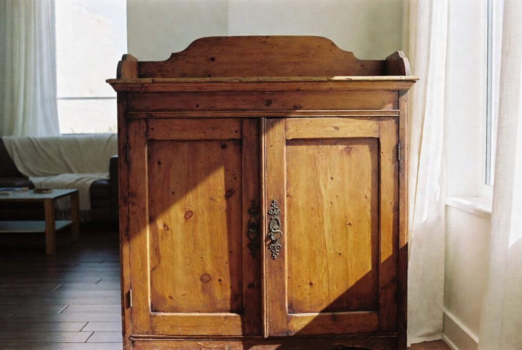 Vintage wooden cabinet with aged patina styled beside modern decor in warm living room, natural light