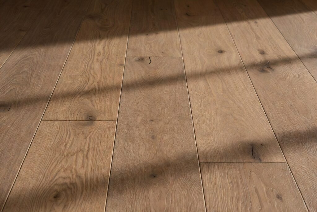 Matte wire-brushed oak floor surface close-up showing natural grain and warm texture, soft diffused daylight