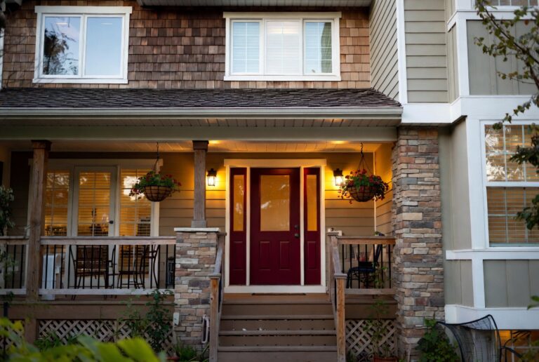 Welcoming home exterior with bold front door, mixed materials and warm porch lighting