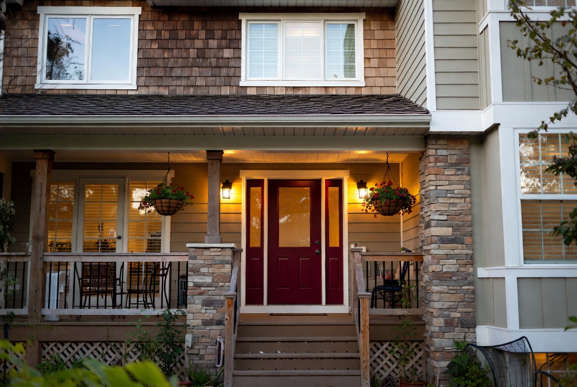 Welcoming home exterior with bold front door, mixed materials and warm porch lighting