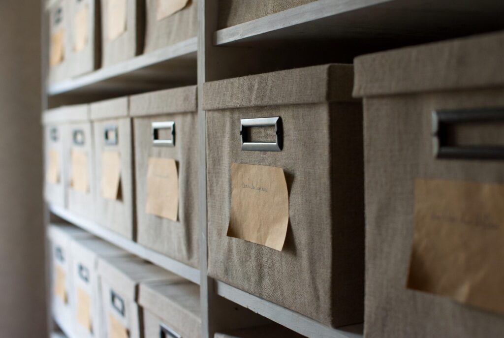 Close-up neat kraft paper labels on matching linen storage boxes on shelf, soft natural light, organized home storage
