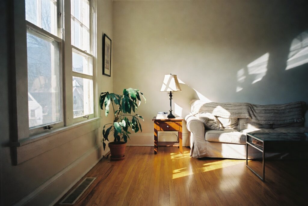 Bright living room with warm honey oak hardwood floors, soft cream walls and natural furniture, afternoon light