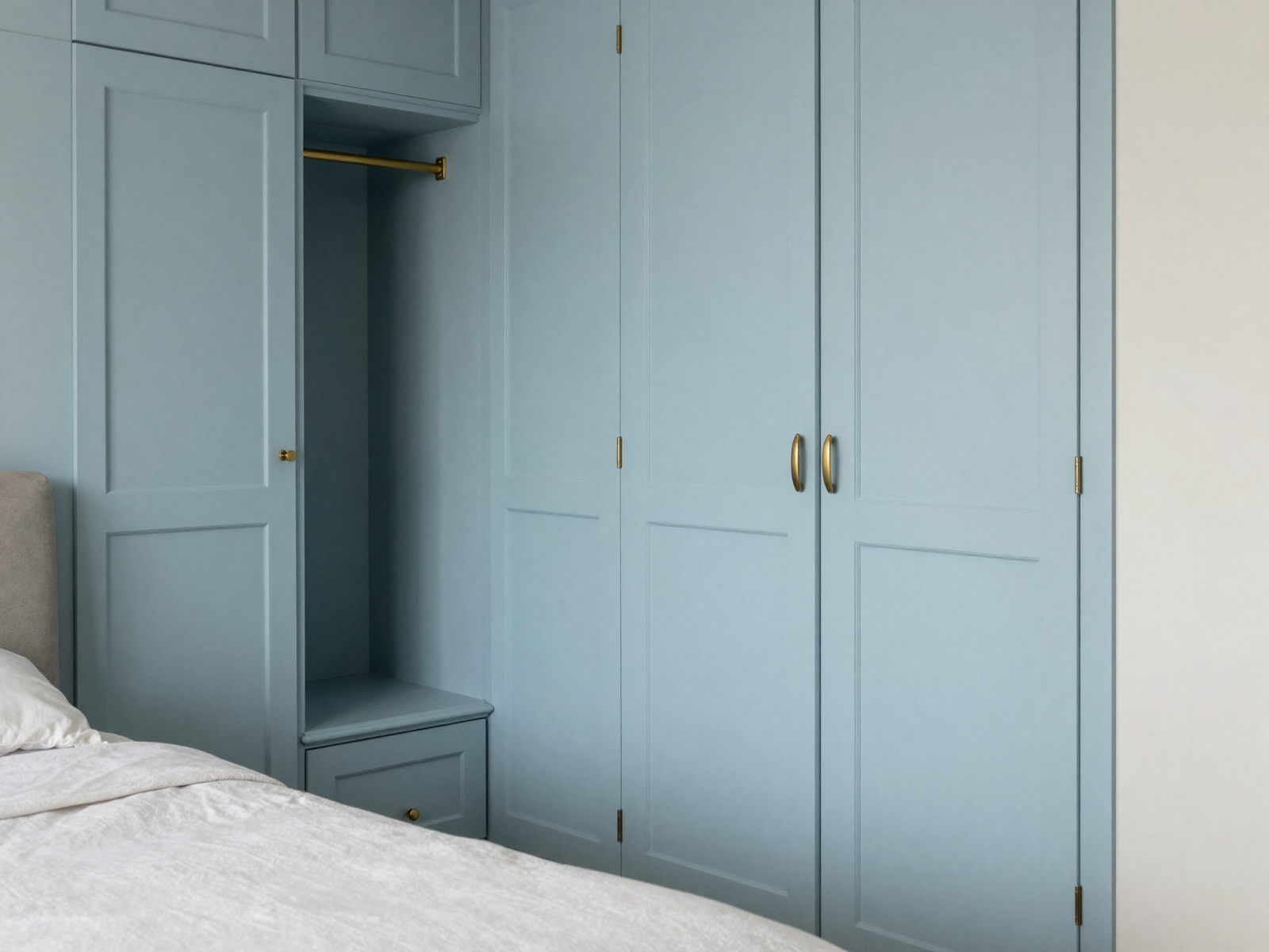 Built-in bedroom wardrobe nook with powder blue paint and brass hardware