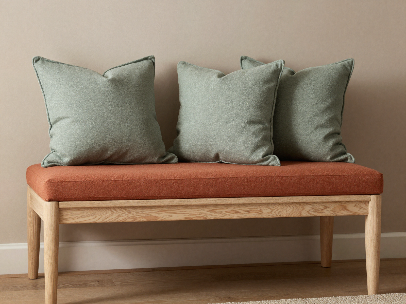 Bedroom bench with terracotta cushion and sage green pillows