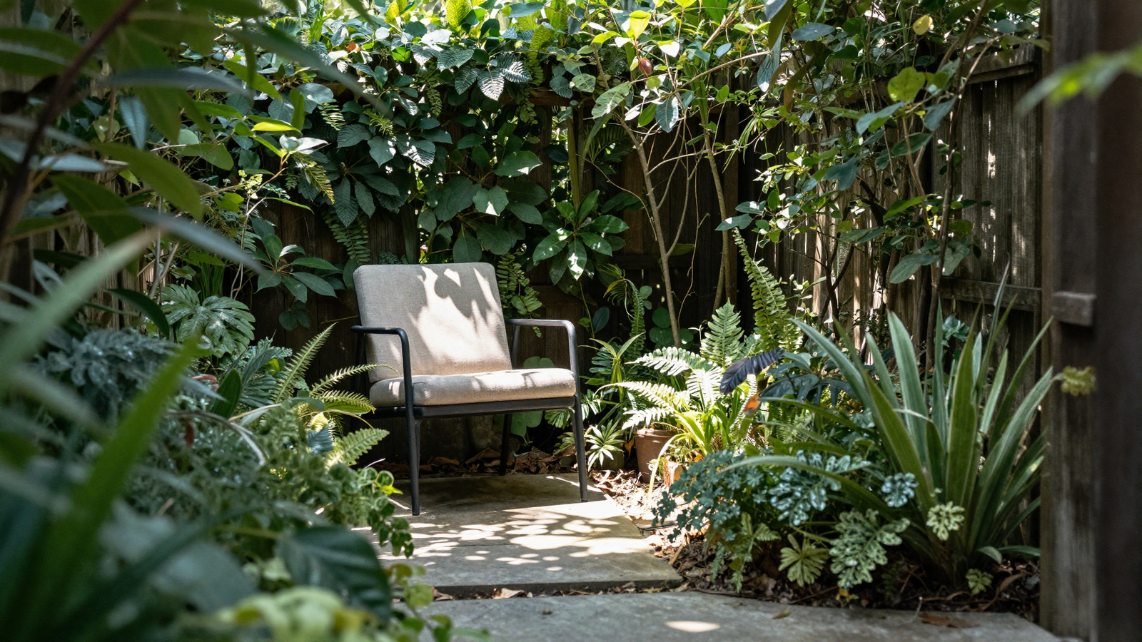 Intimate garden nook with a single comfortable chair tucked into dense planting