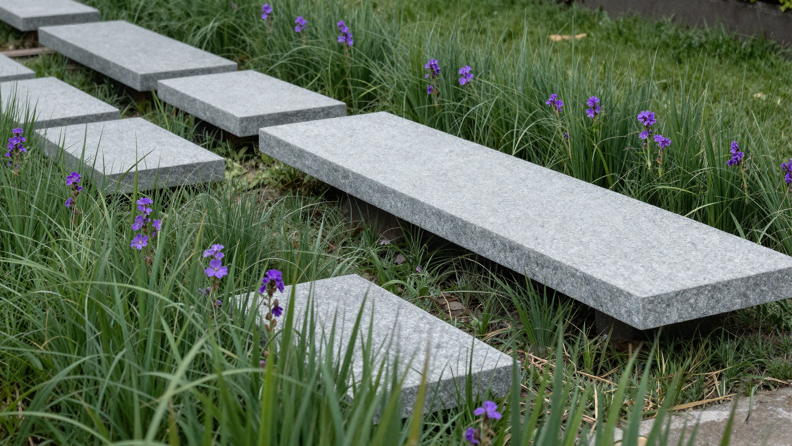 Rectangular stone slabs hovering inside a raised ornamental grass platform