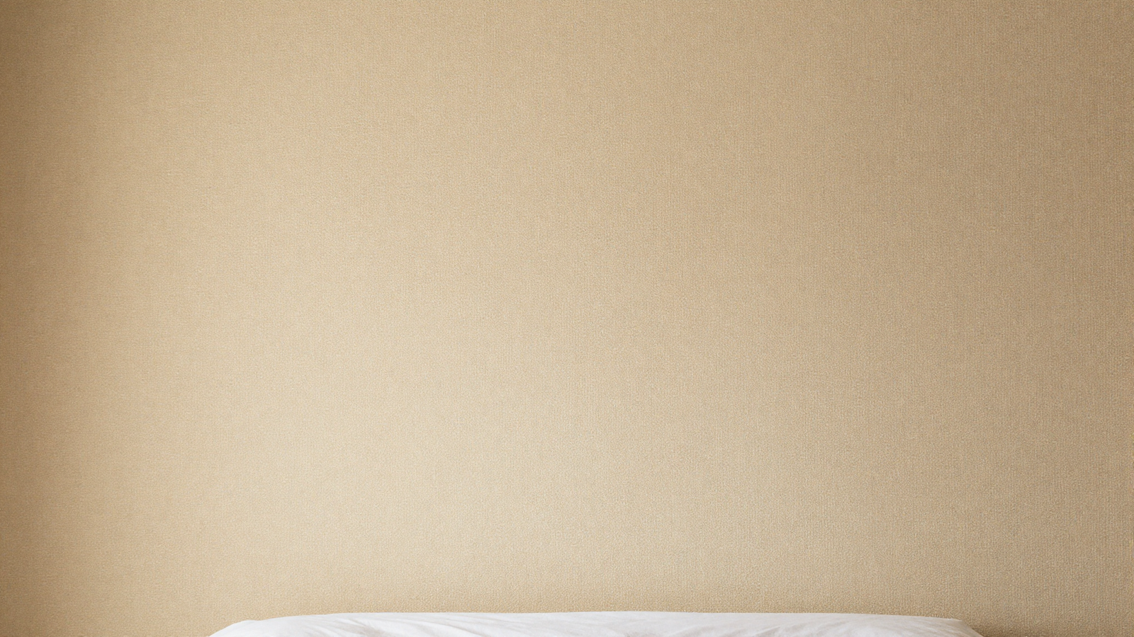 Bedroom wall with textured grasscloth wallpaper in warm sandy beige tone