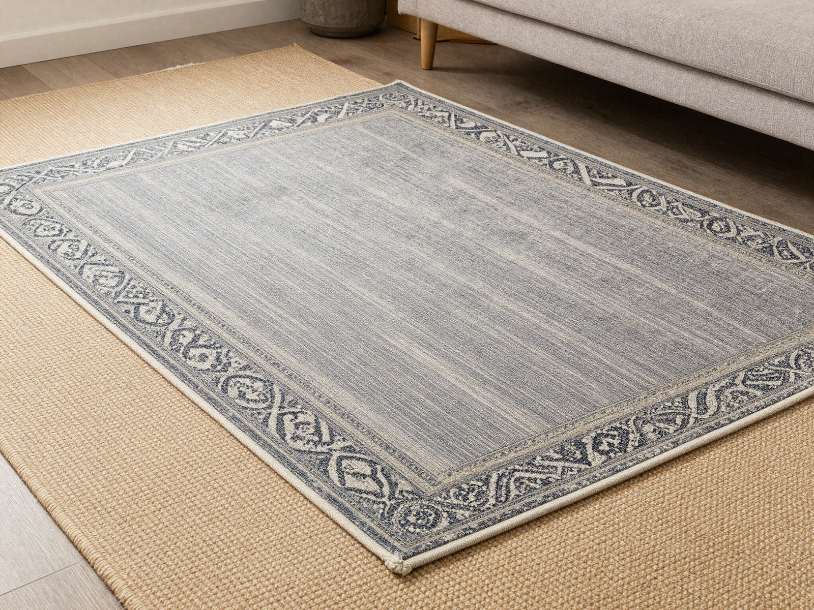 Patterned wool rug layered over a flat woven jute rug