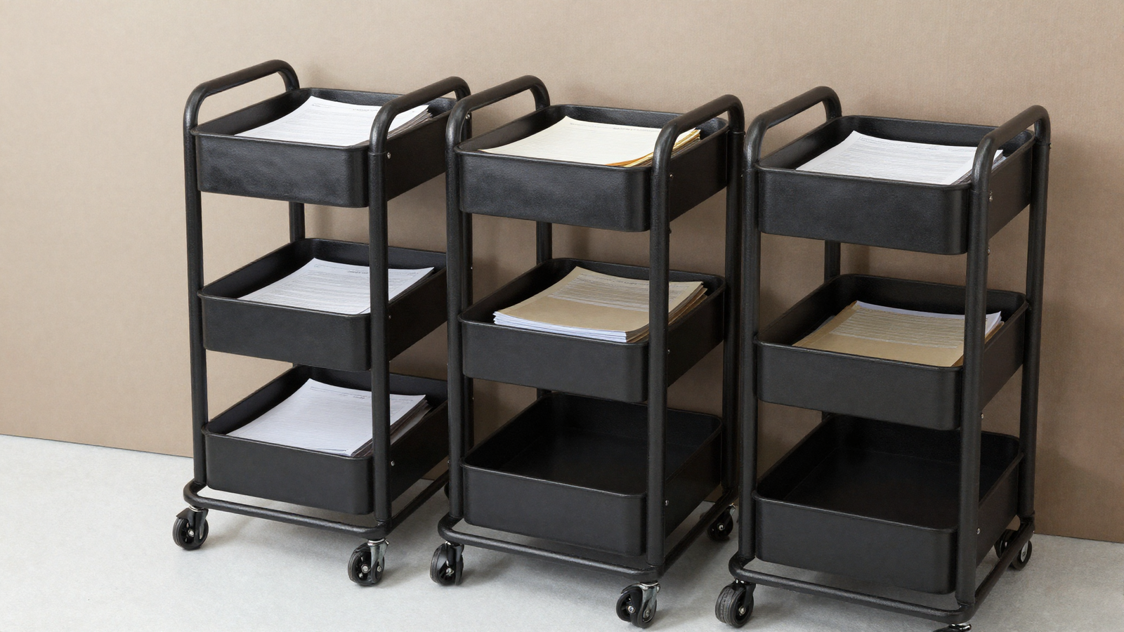 Rolling black metal utility cart with multiple tiers holding office supplies and files