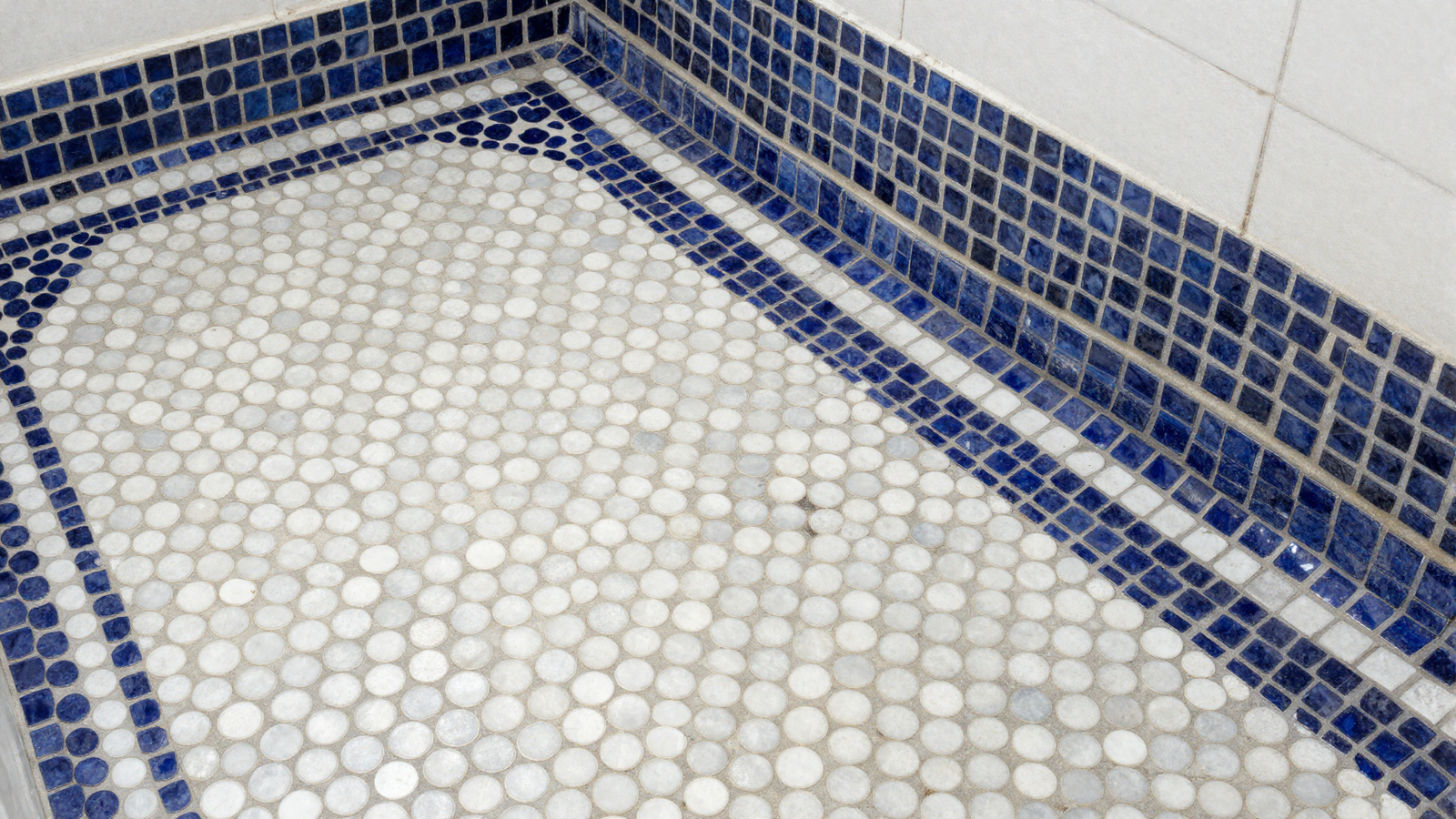 Bathroom floor with two-toned penny tile in navy blue and white round mosaic pattern