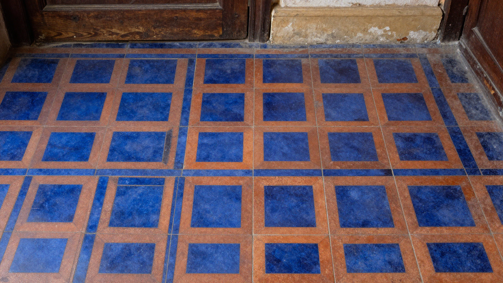 Entryway floor with patterned encaustic-style tile in deep blue and terracotta geometric design