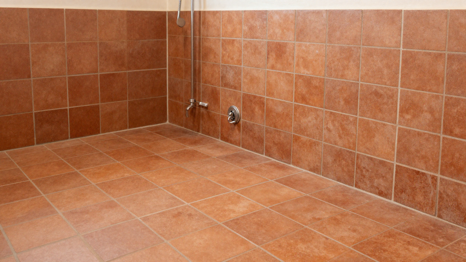 Bathroom with tile drenching technique using continuous terracotta tile across floor walls and shower