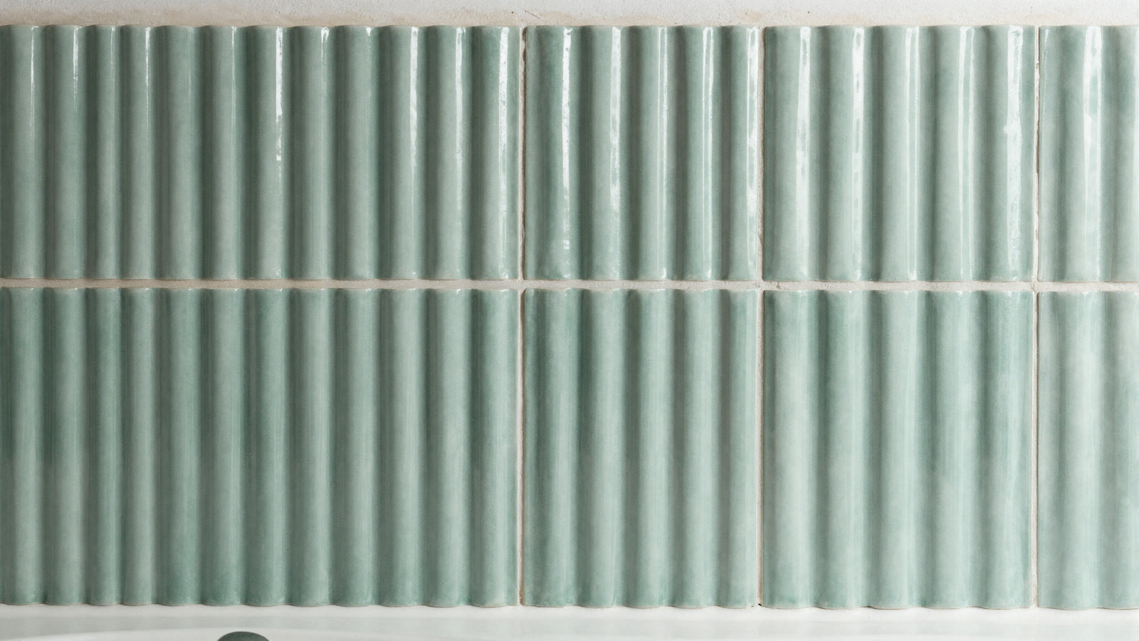 Bathroom accent wall with fluted ribbed tile in sage green catching light