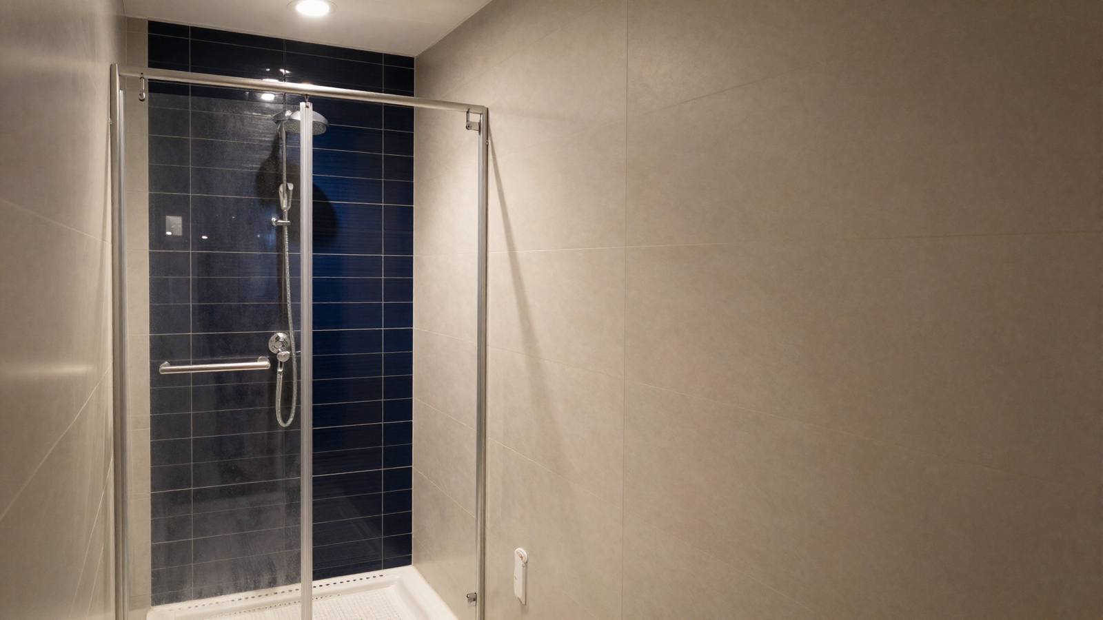Walk-in shower with light tile walls and one dark midnight blue tiled back corner