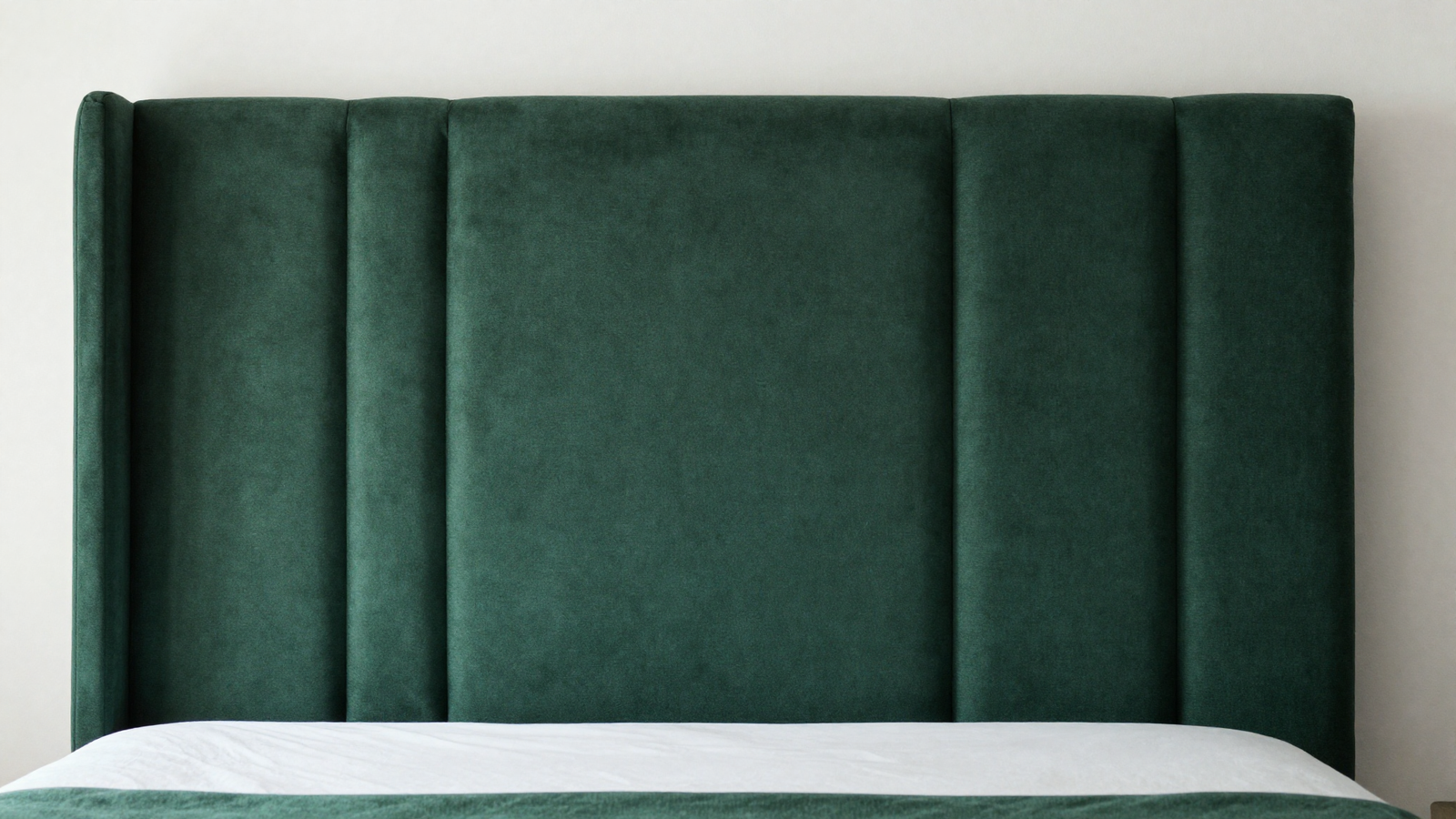 Bedroom with wall-to-wall upholstered headboard in deep green fabric spanning the entire wall