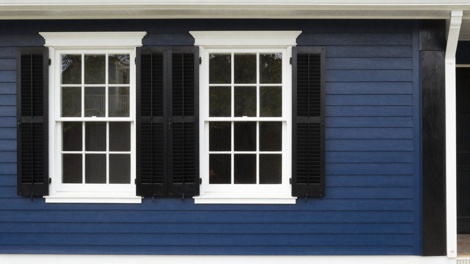 House exterior with deep navy blue siding and white trim with black semi-gloss shutters