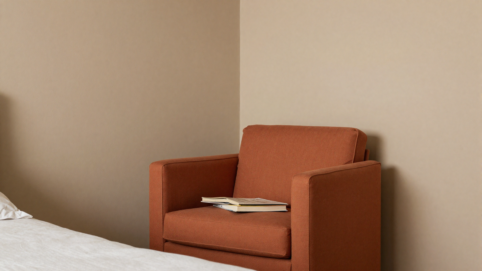 Bedroom corner with terracotta upholstered armchair against beige walls