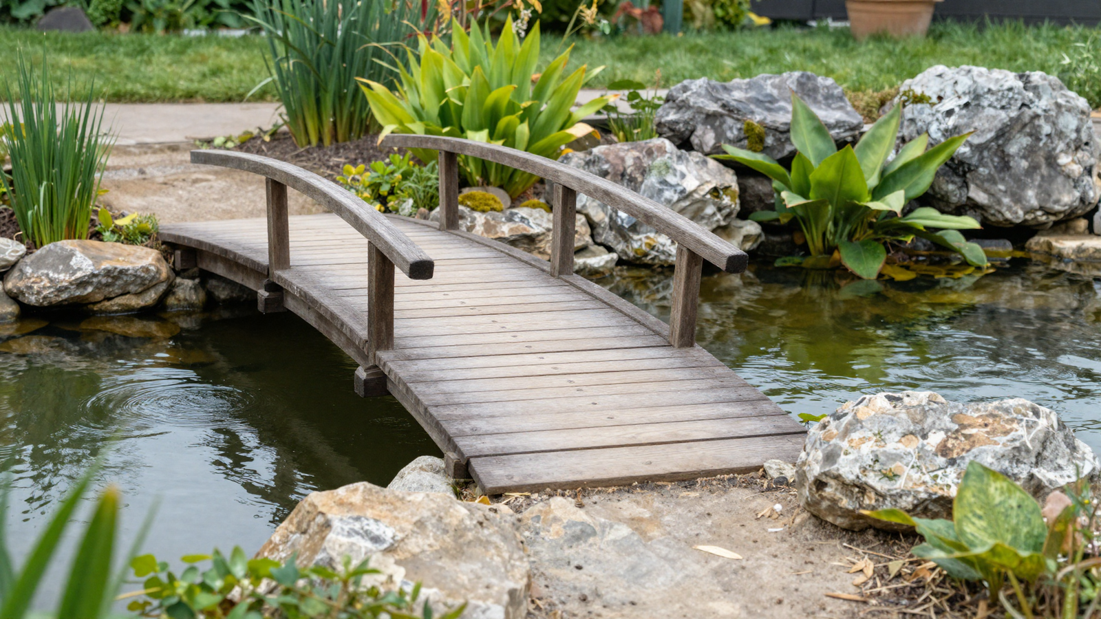 Small wooden bridge crossing a backyard garden pond