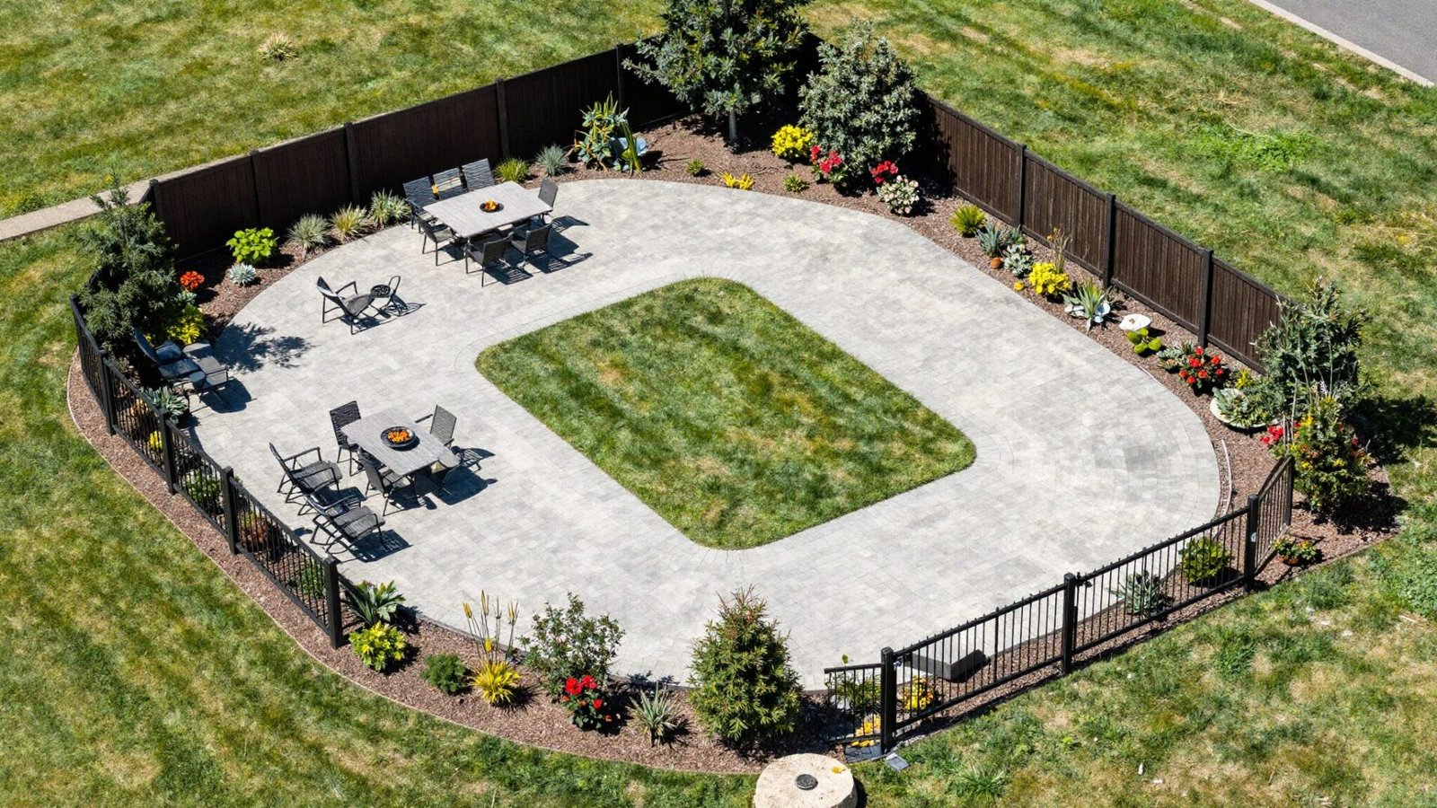 Aerial view of a backyard divided into zones with different paving materials marking dining lounge and fire pit areas