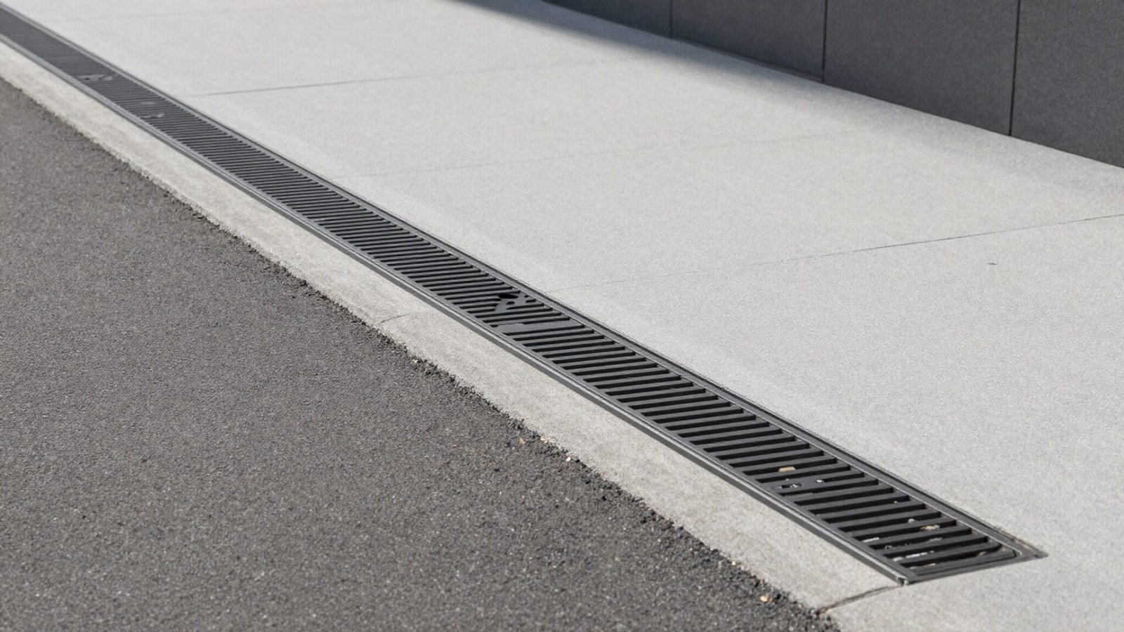 Sleek linear drain channel with modern decorative metal grate integrated along a driveway edge
