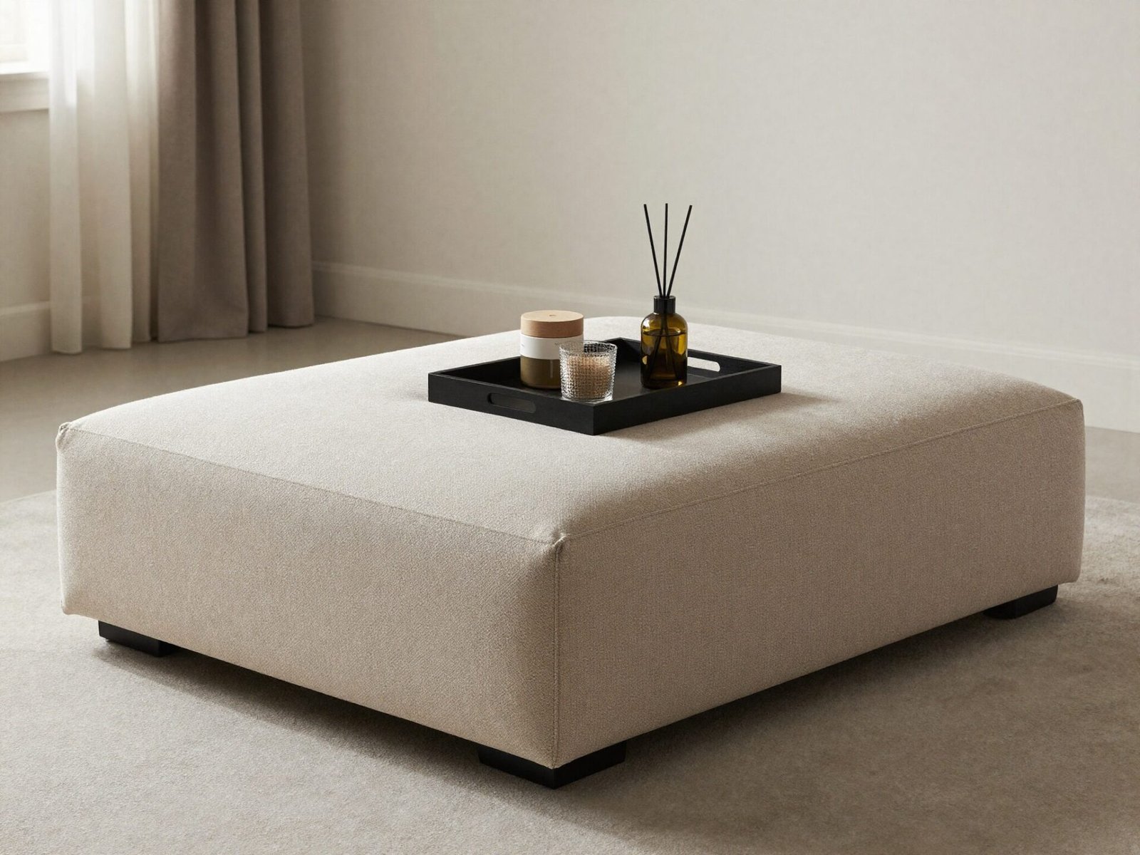 Large upholstered ottoman used as a coffee table with a tray on top