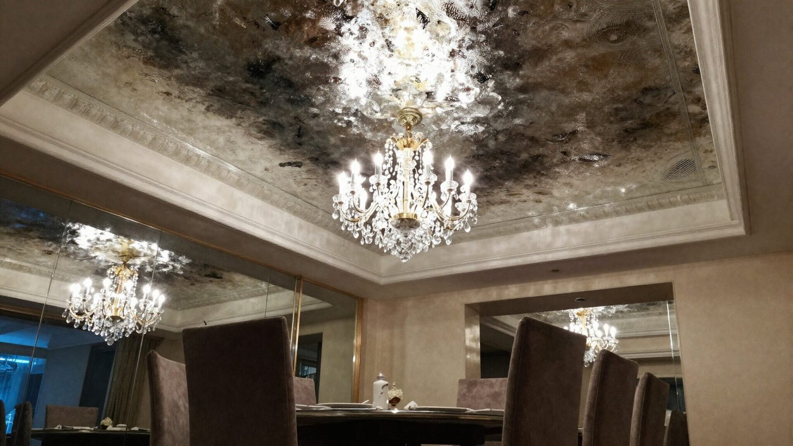 Dining room with high-gloss reflective ceiling finish reflecting chandelier light