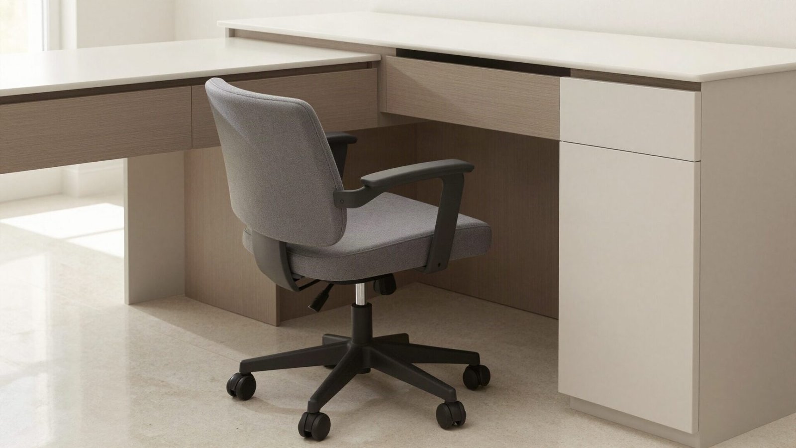 Compact ergonomic task chair tucked neatly into a custom built-in vanity desk knee-hole in a small modern bathroom.