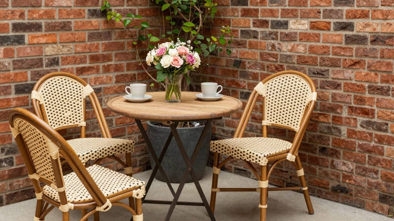 Teak French bistro dining set on a compact gravel patio surrounded by lush foliage