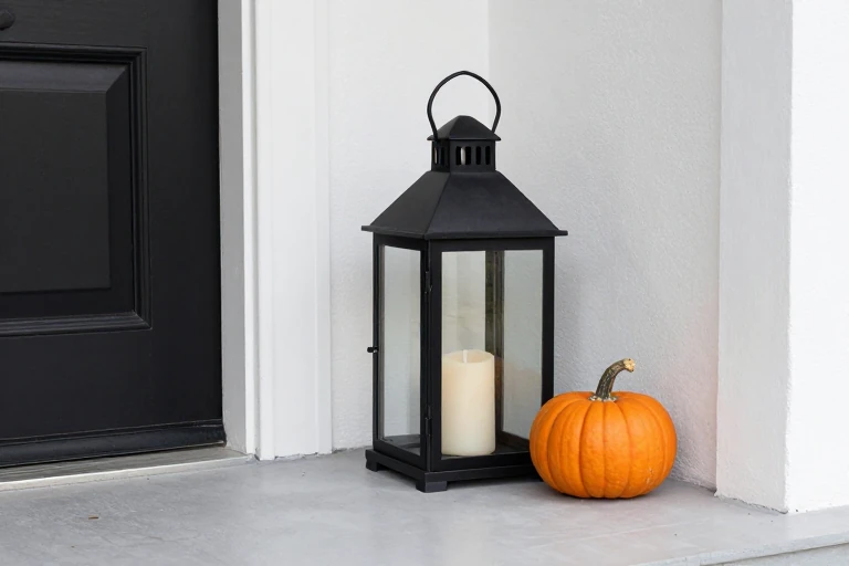 Dark metal lantern placed safely beside fall pumpkins